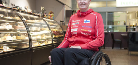 Marjaana Heikkinen kahvilan kakkuvitriinien edessä.