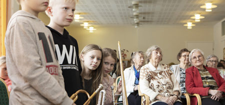 Kalevalan koulun 5A-musiikkiluokan oppilaat Matti Kärkkäinen, Topi Toivanen, Alma Tiitinen ja Terhi Koskenvuori seisovat soittimineen vanhusten vieressä Männistön palvelutalolla.