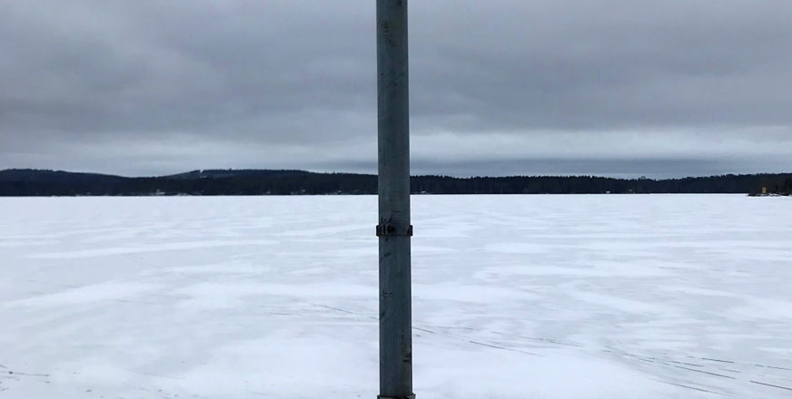 jäätä järven pinnalla ja metalliputki sen edessä pystyssä