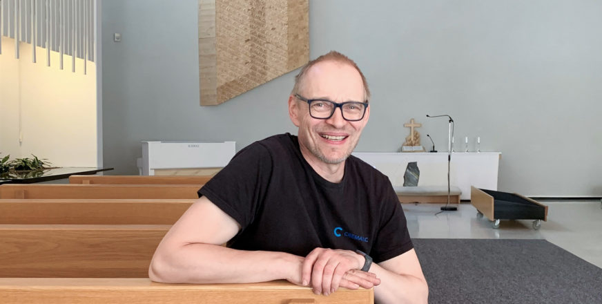 Krematoriomestari Tuomo Korhonen istuu siunauskappelin penkissä taustalla näkyy alttari