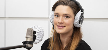 Krista Kosonen kuulokkeet päässä mikrofonin äärellä.