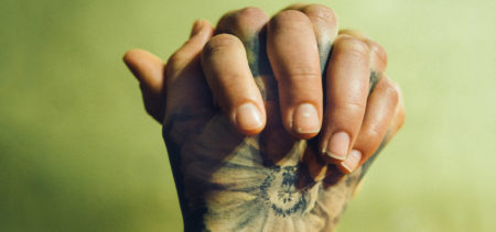 Miehen tatuoidut kädet ristissä.