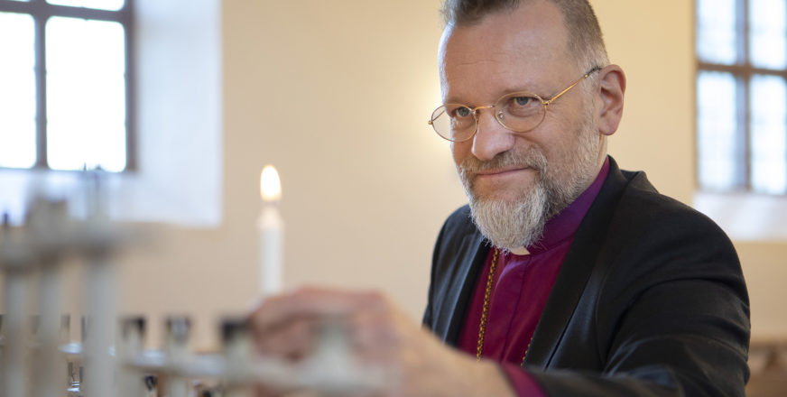 Piispa Jari Jolkkonen sytyttää kunttilän kirkossa.