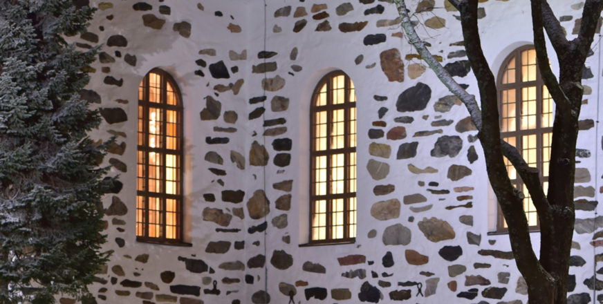 Kuopion tuomiokirkon seinää ja valaistuja ikkunoita