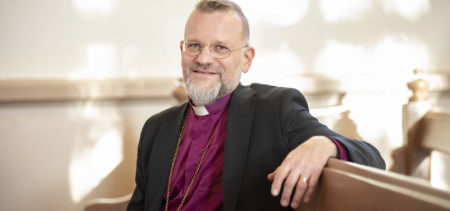 Piispa Jari Jolkkonen istuu kirkonpenkissä