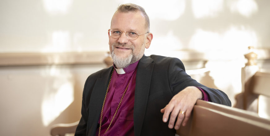 Piispa Jari Jolkkonen istuu kirkonpenkissä
