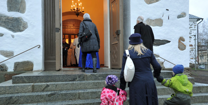 Ihmisiä menossa Kuopion tuomiokirkon ovesta sisään.