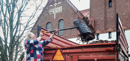 Työntekijä heittää lehtiroskia traktorin kytiin Siilinjärven kirkon edessä