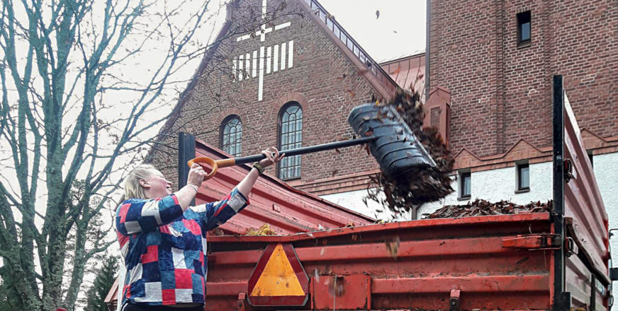 Työntekijä heittää lehtiroskia traktorin kytiin Siilinjärven kirkon edessä