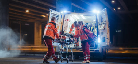 Ensihoitohenkilöstö työntää paareja ambulanssiin