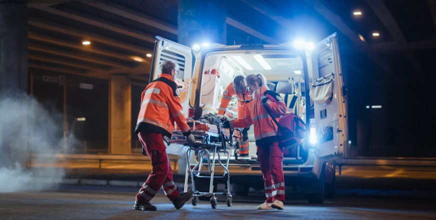 Ensihoitohenkilöstö työntää paareja ambulanssiin