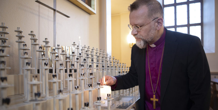 Piispa Jari Jolkkonen sytyttämässä kynttilää kirkossa