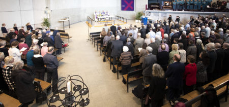 Paljon ihmisiä istuu kirkkosalissa, kuva Alavan kirkosta.