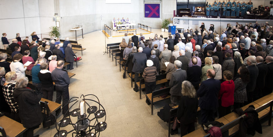Paljon ihmisiä istuu kirkkosalissa, kuva Alavan kirkosta.