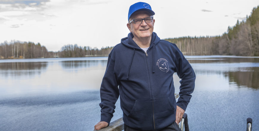 Hannu Koskelainen lenkkeilyasussa laiturilla, taustalla tyyni lammen pinta