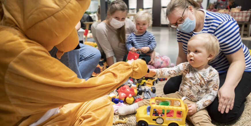 Kaksi äitiä lapsineen leikkii lattialla