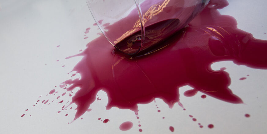 Kaatunut viinilasi, viini levinnyt pöydälle.