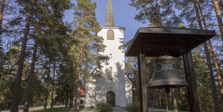 Riistaveden kirkko ja kellotorni puiden keskellä kesällä.