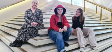 Kolme ihmistä istuu Kuopion kaupunginteatterin sisäportailla.