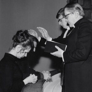mustavalkoisessa kuvassa mies ja nainen ovat polvistuneena alttarilla, molempien pään päällä pitää kättään pappi