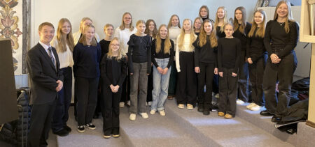 Nuorisokuorolaiset eli ryhmä tyttöjä ja kuoronjohtaja Vesa Kajava seisovat Siilinjärven kirkon parvella