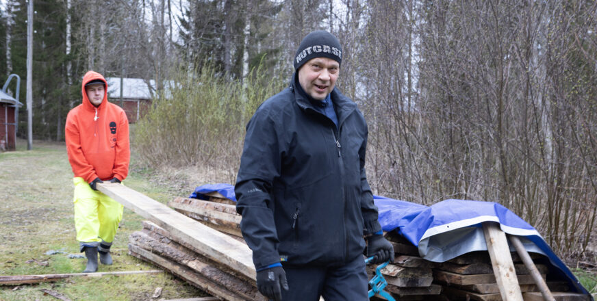 Miehet kantavat pitkospuulankkuja varastoon kuivumaan.