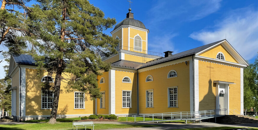 Keltainen puukirkko kesällä.