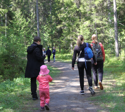 Perheitä metsäpolulla kävelemässä.