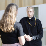 Sairaalapappi keskustelee naisen kanssa Kuopion yliopistollisen sairaalan käytävällä.