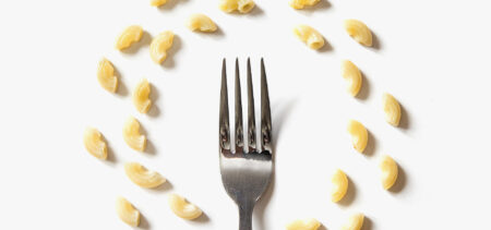 Pöydällä on haarukka, jonka ympärillä on kaksi makaroneista muodostettua ympyrää