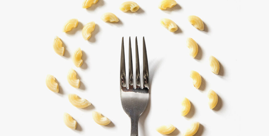 Pöydällä on haarukka, jonka ympärillä on kaksi makaroneista muodostettua ympyrää