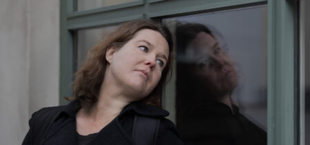 Anna Miinin nojaa päätään ikkunalasiin sivulle katsoen.