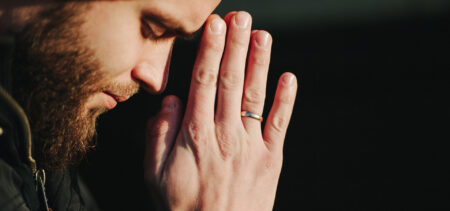 Sivuttainen kasvokuva rukoilevasta miehestä.