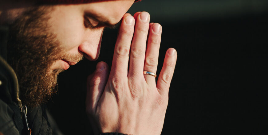 Sivuttainen kasvokuva rukoilevasta miehestä.