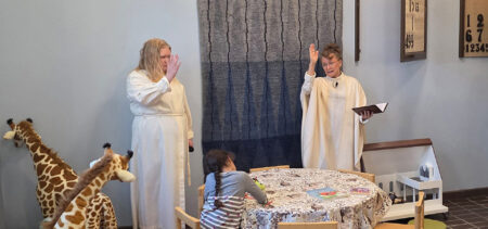 Kaksi albaan pukeutunutta naista, joista toinen pastori Laurinkari, siunaavat käyttöön Siilinjärven lastenpaikan.