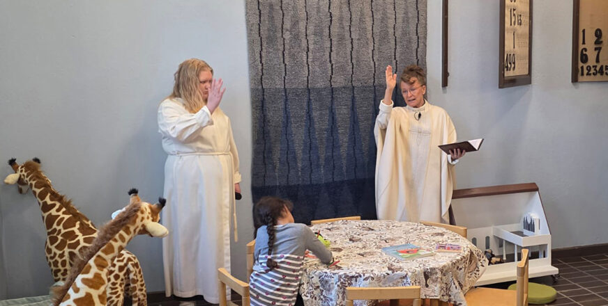 Kaksi albaan pukeutunutta naista, joista toinen pastori Laurinkari, siunaavat käyttöön Siilinjärven lastenpaikan.