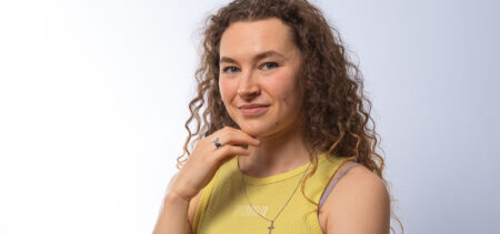 Ella Junnila hymyilee hieman ja hänen kaulassaan roikkuu ristikoru.