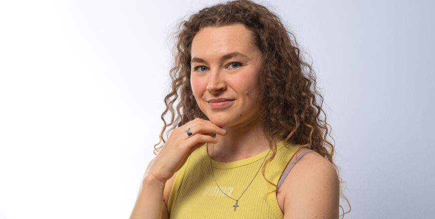 Ella Junnila hymyilee hieman ja hänen kaulassaan roikkuu ristikoru.