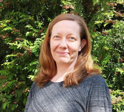 Tiia Ngandu hymyilee kasvokuvassa, taustalla puita.