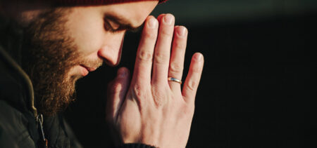 Sivuprofiili miehestä, joka rukoilee kämmenet nostettuna kasvojen eteen.