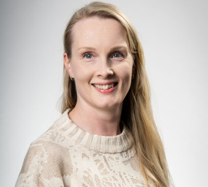 Henkilö katsoo kameraan hymyillen.