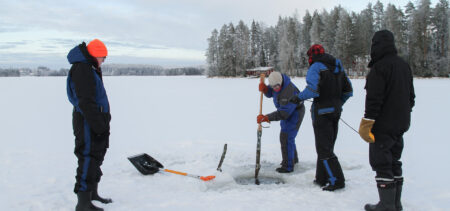 Neljä ihmistä kalastamassa järven jäällä.