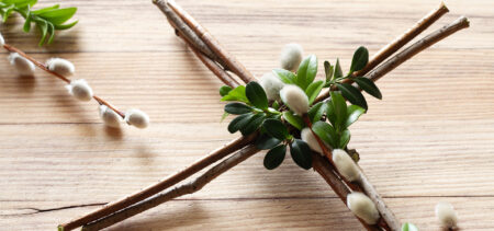 Puisella pöydällä oksista tehty ristikoriste, jossa mukana myös pajunkissoja.