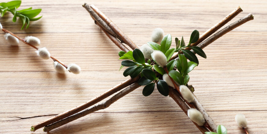 Puisella pöydällä oksista tehty ristikoriste, jossa mukana myös pajunkissoja.