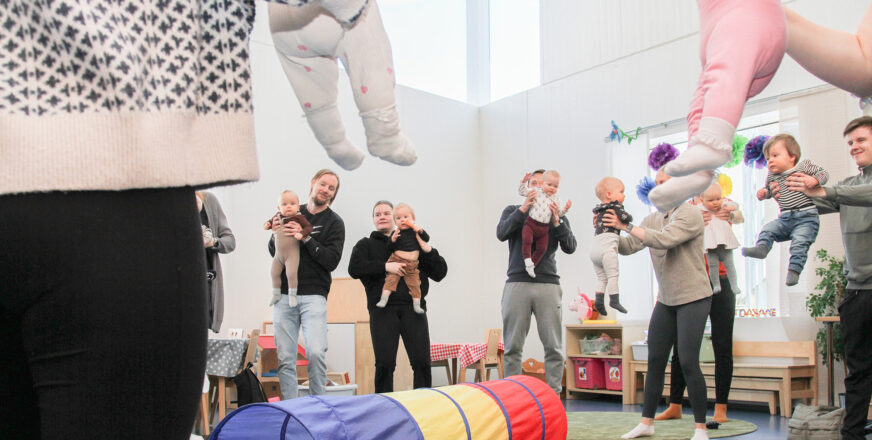 Vanhemmat ja vauvat leikkimässä ringissä.