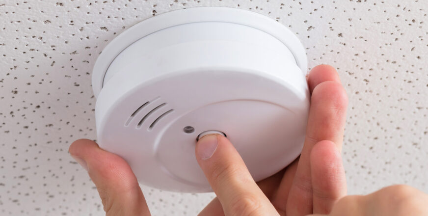 Käsi ja palovaroitin.