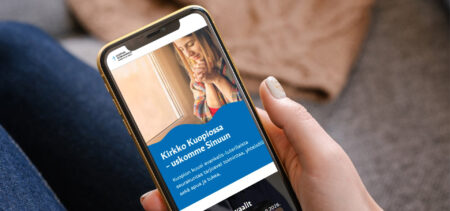 Puhelin kädessä, siinä auki Kuopion seurakuntien verkkosivut.