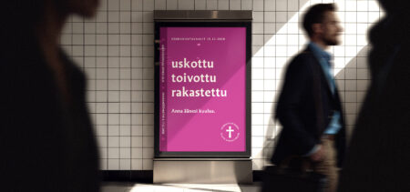 Käytävän seinässä on seurakuntavaalien Uskottu toivottu rakastettu -tekstillä varustettu mainos, jonka ohi kulkee ihmisiä.