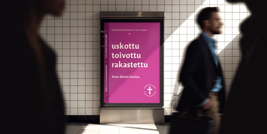 Käytävän seinässä on seurakuntavaalien Uskottu toivottu rakastettu -tekstillä varustettu mainos, jonka ohi kulkee ihmisiä.