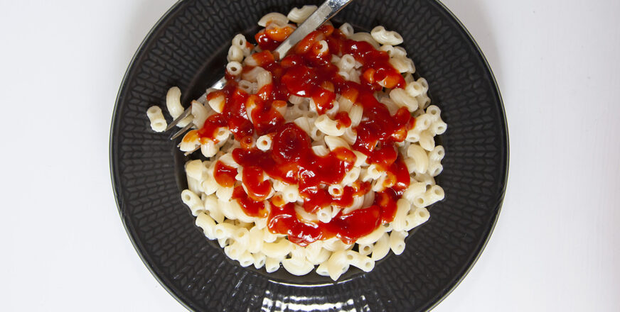 Lautasellinen makaronia, jonka päällä ketsuppia